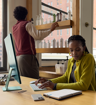 شخص يجلس إلى مكتب في صالون للشعر ويعمل على iMac‏